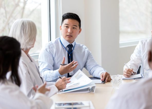 Male hospital administrator gestures while discussing a serious topic during a staff meeting.